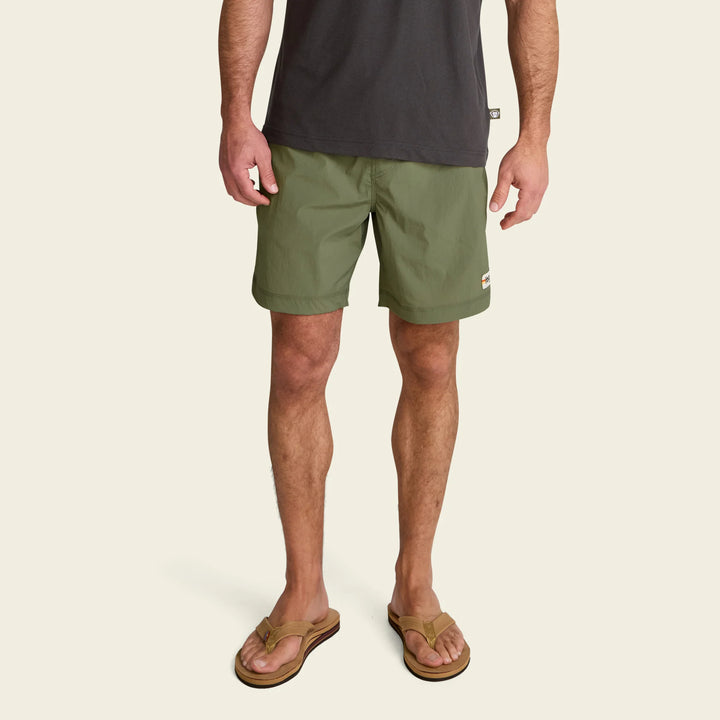 Person wearing green shorts and a dark shirt on a beige background