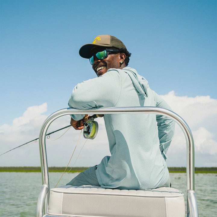 Man fishing on a boat with a clear sky and water background