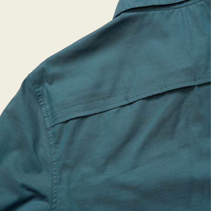 Close-up of a teal shirt collar on a beige background