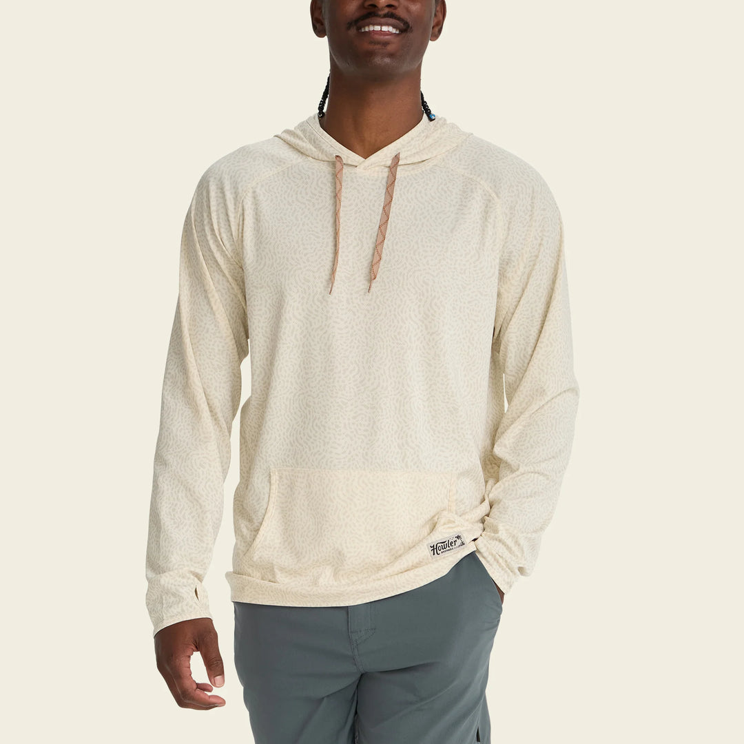 Man wearing a beige hoodie with a brand logo on a beige background