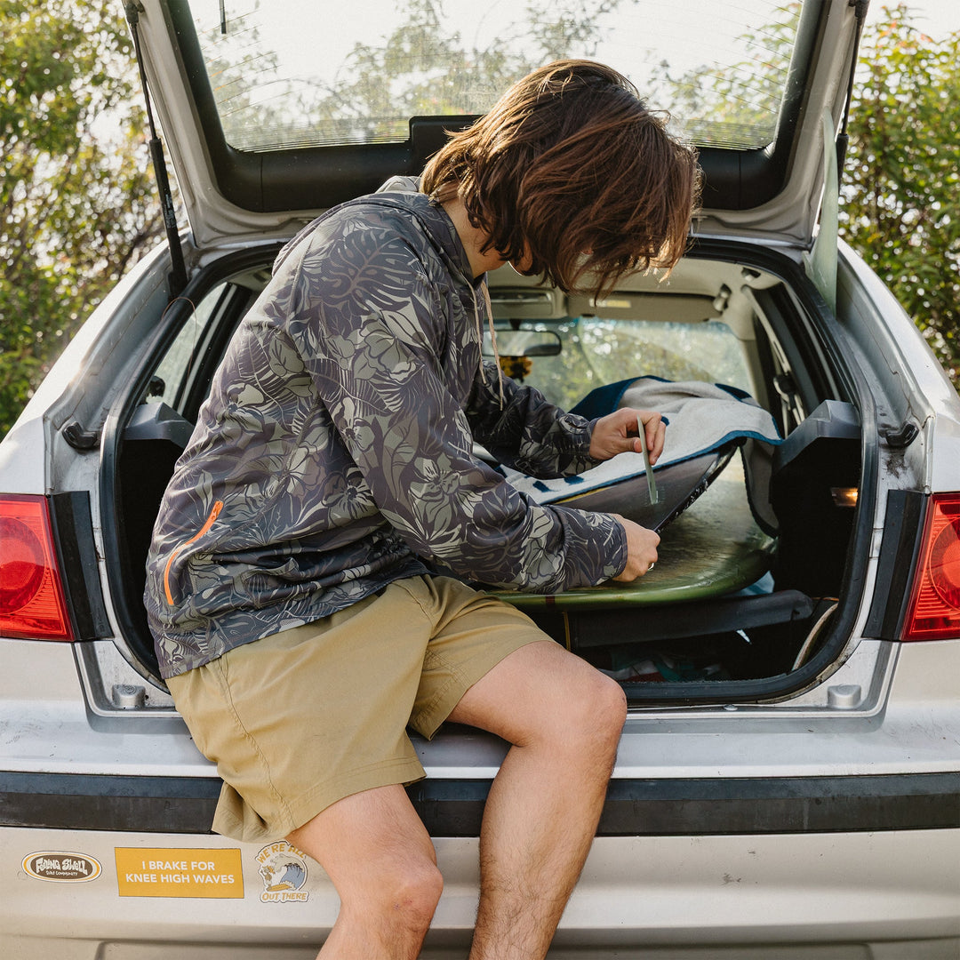 Person sitting in the open trunk of a car, organizing items.