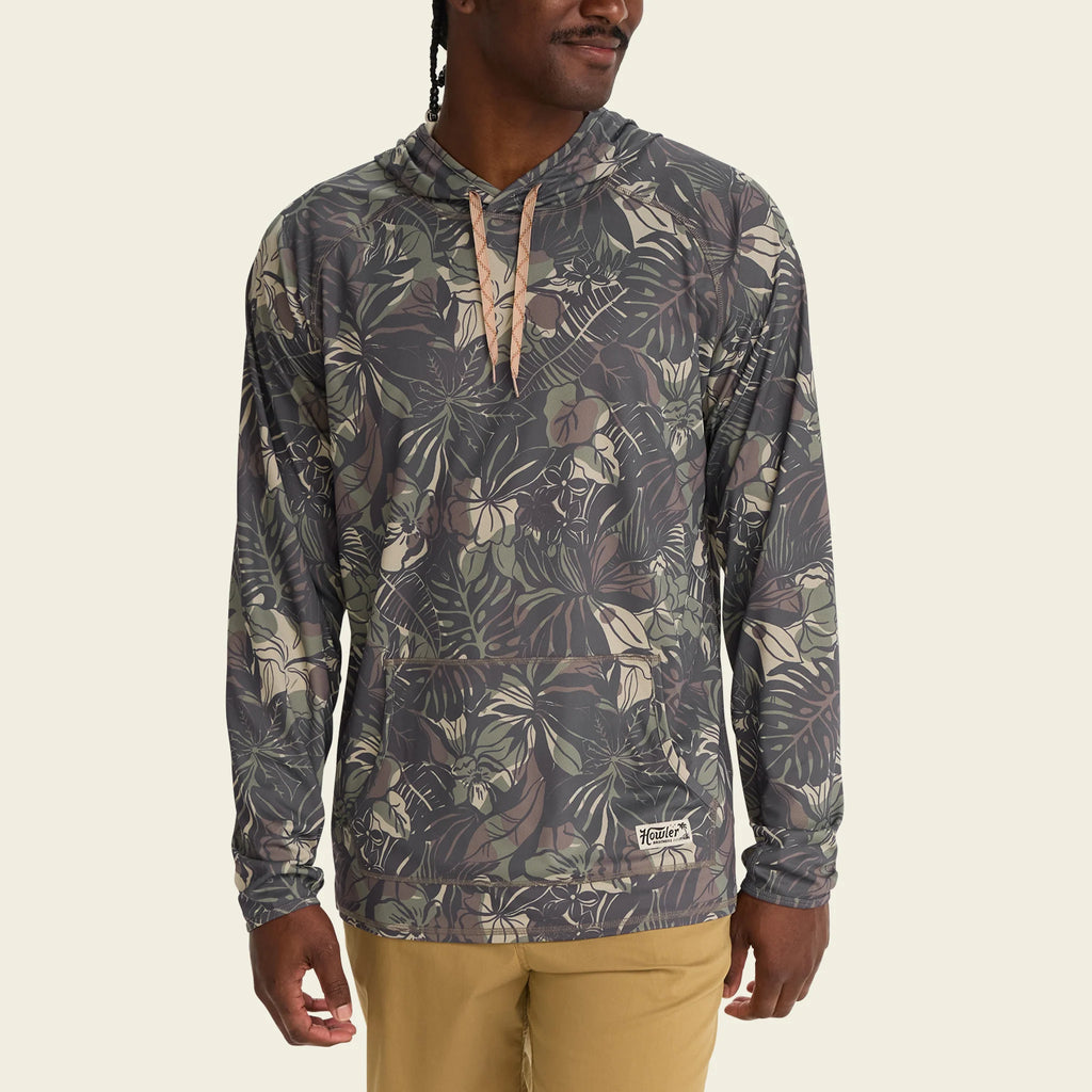 Person wearing a patterned hoodie with a visible brand logo on a beige background