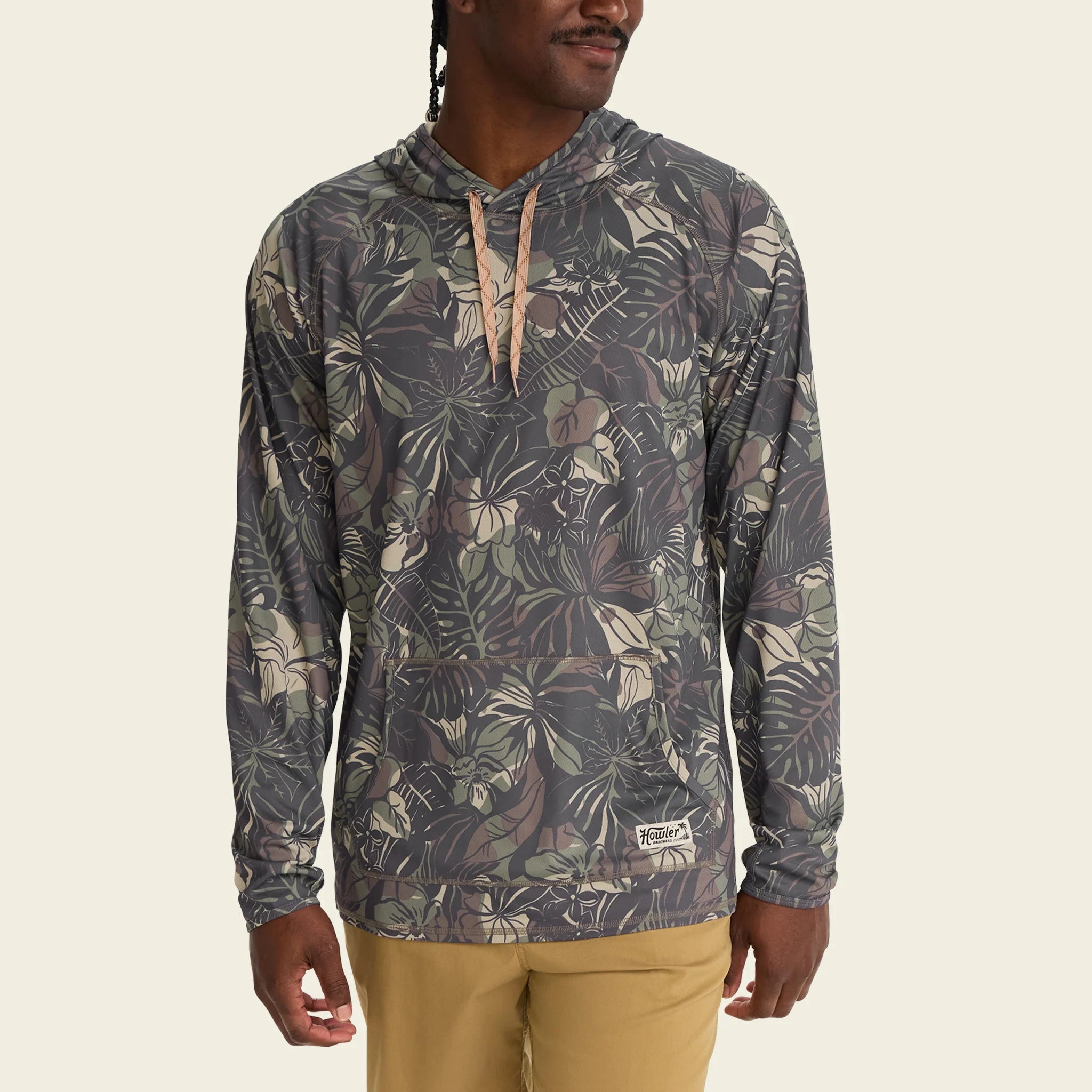Person wearing a patterned hoodie with a visible brand logo on a beige background