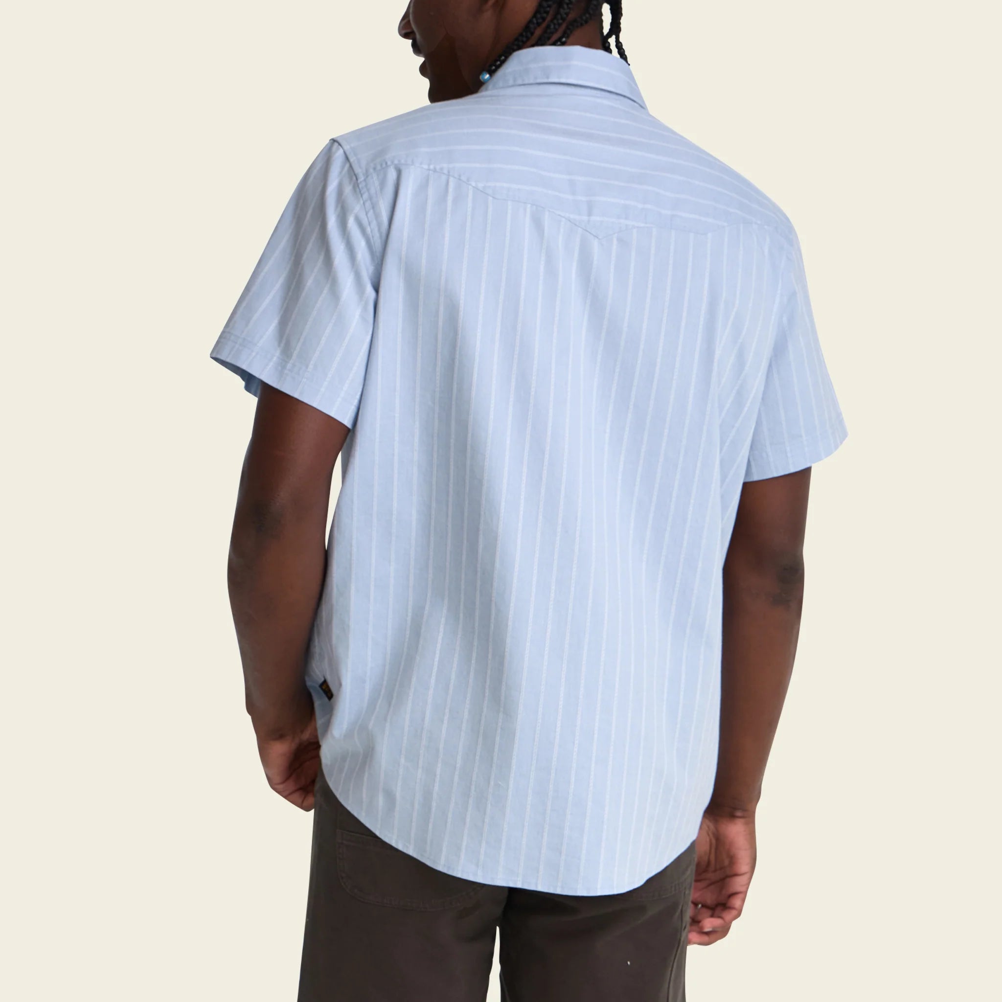 Person wearing a light blue striped shirt on a beige background