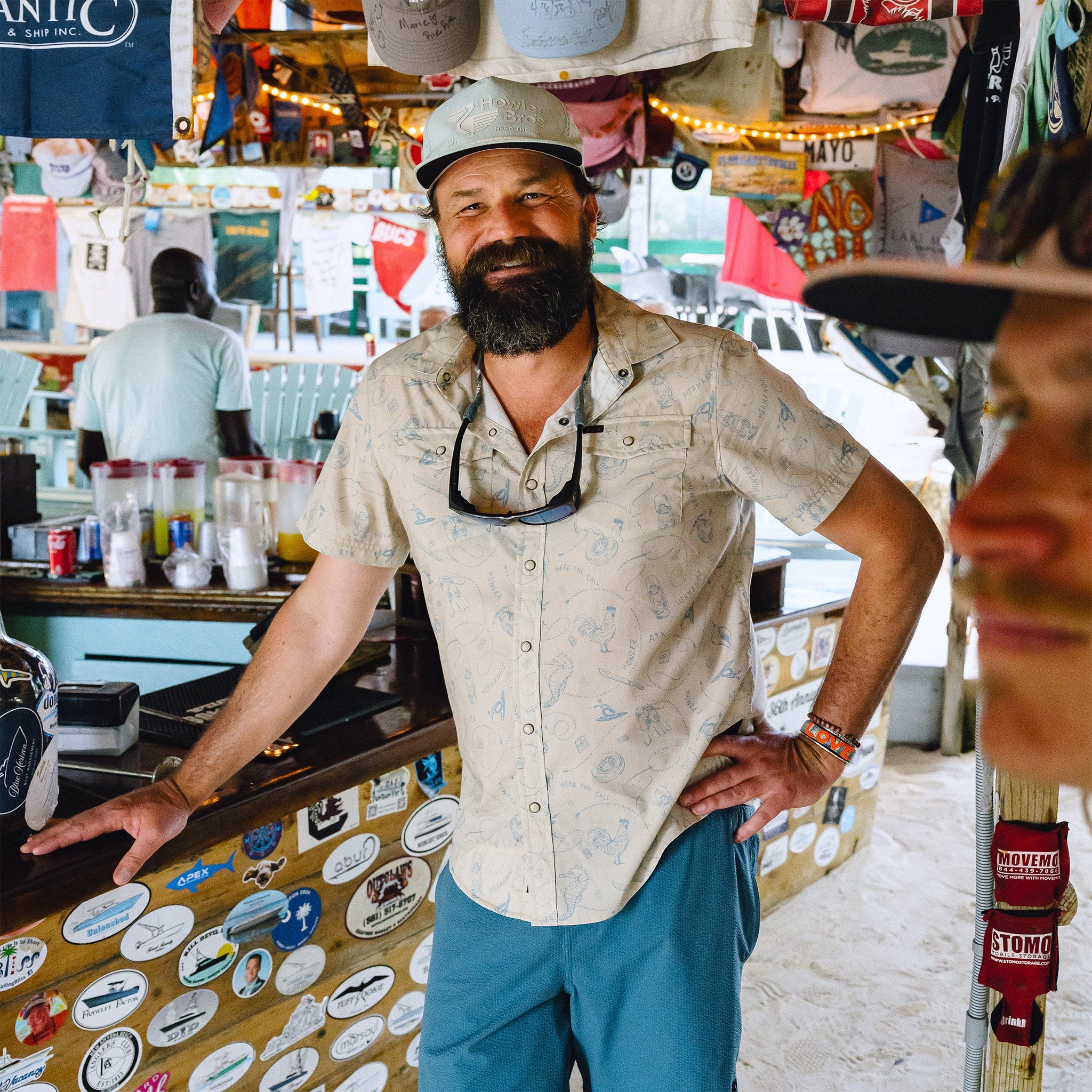 Man with a beard and hat standing in a colorful store interior