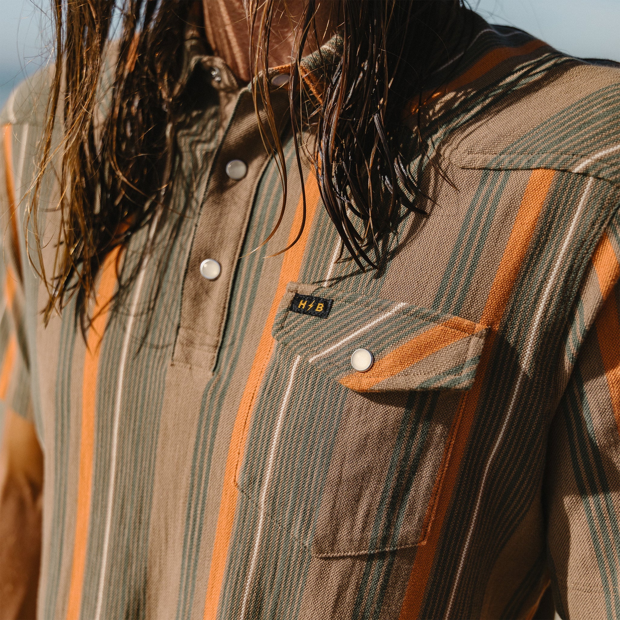 Close-up of a person wearing a striped shirt with a visible brand logo.