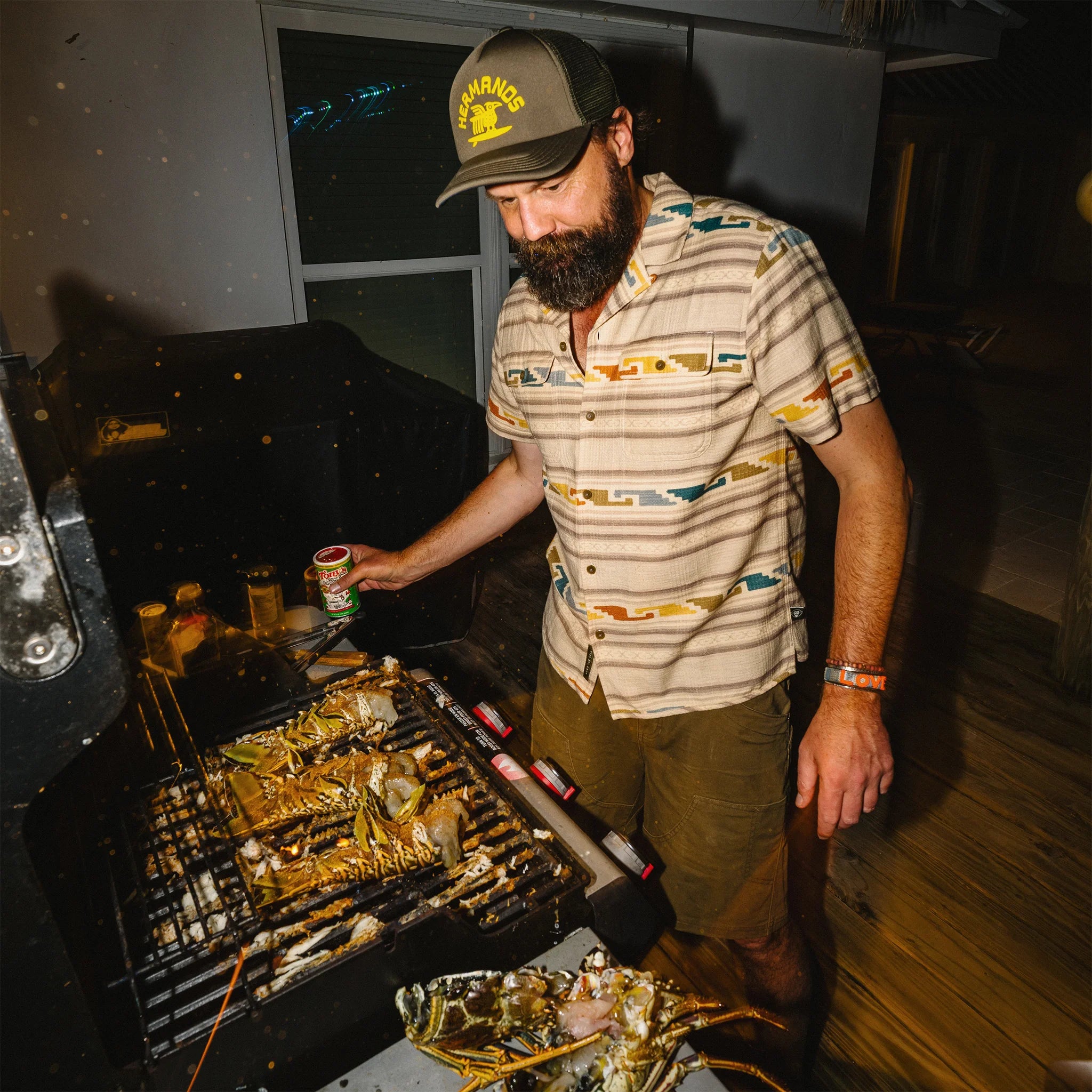 Man grilling food at night with a grill and outdoor setting.