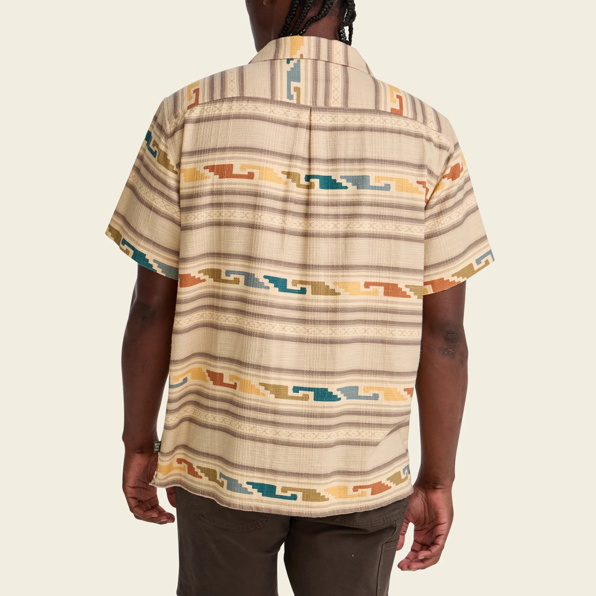 Person wearing a patterned shirt on a beige background