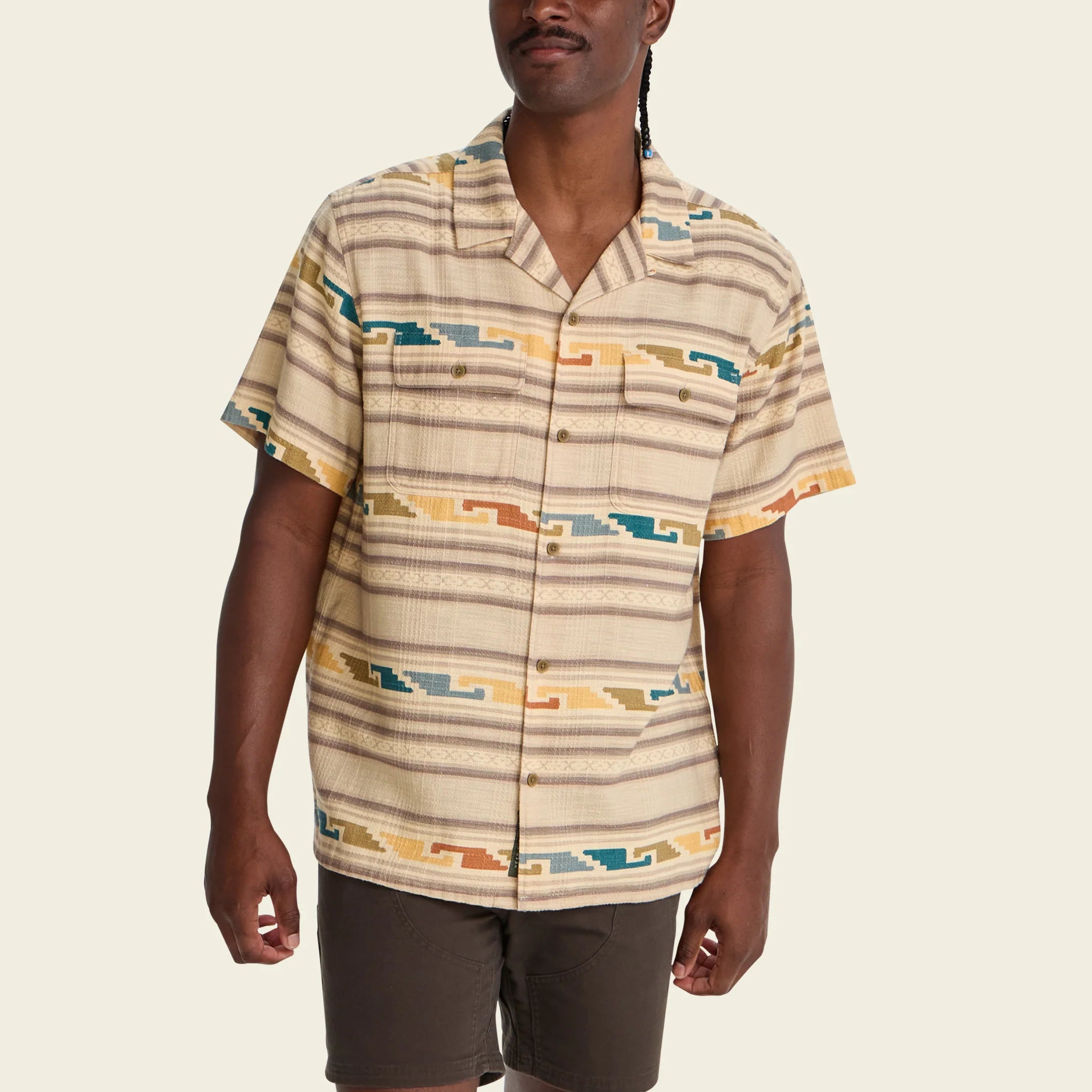 Man wearing a patterned shirt with a neutral background