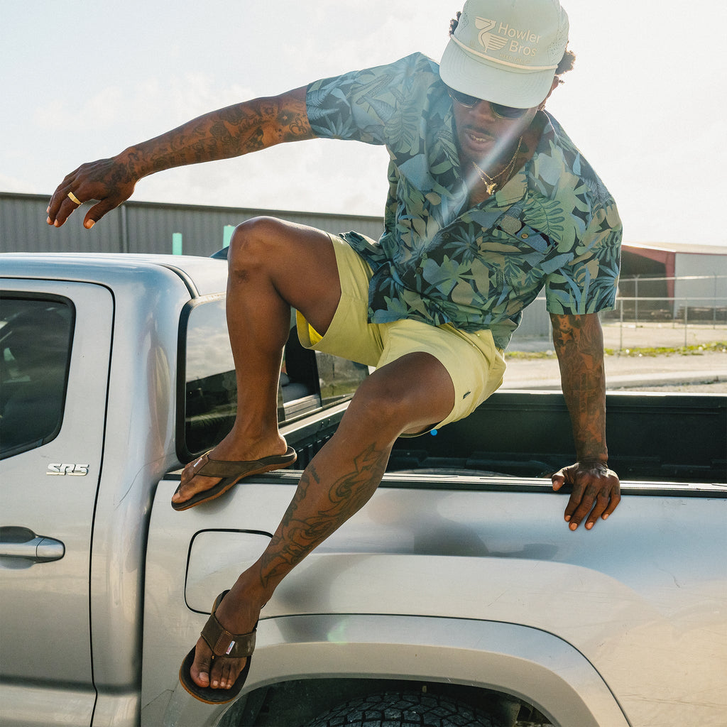 Man sitting on a truck with tattoos and a floral shirt
