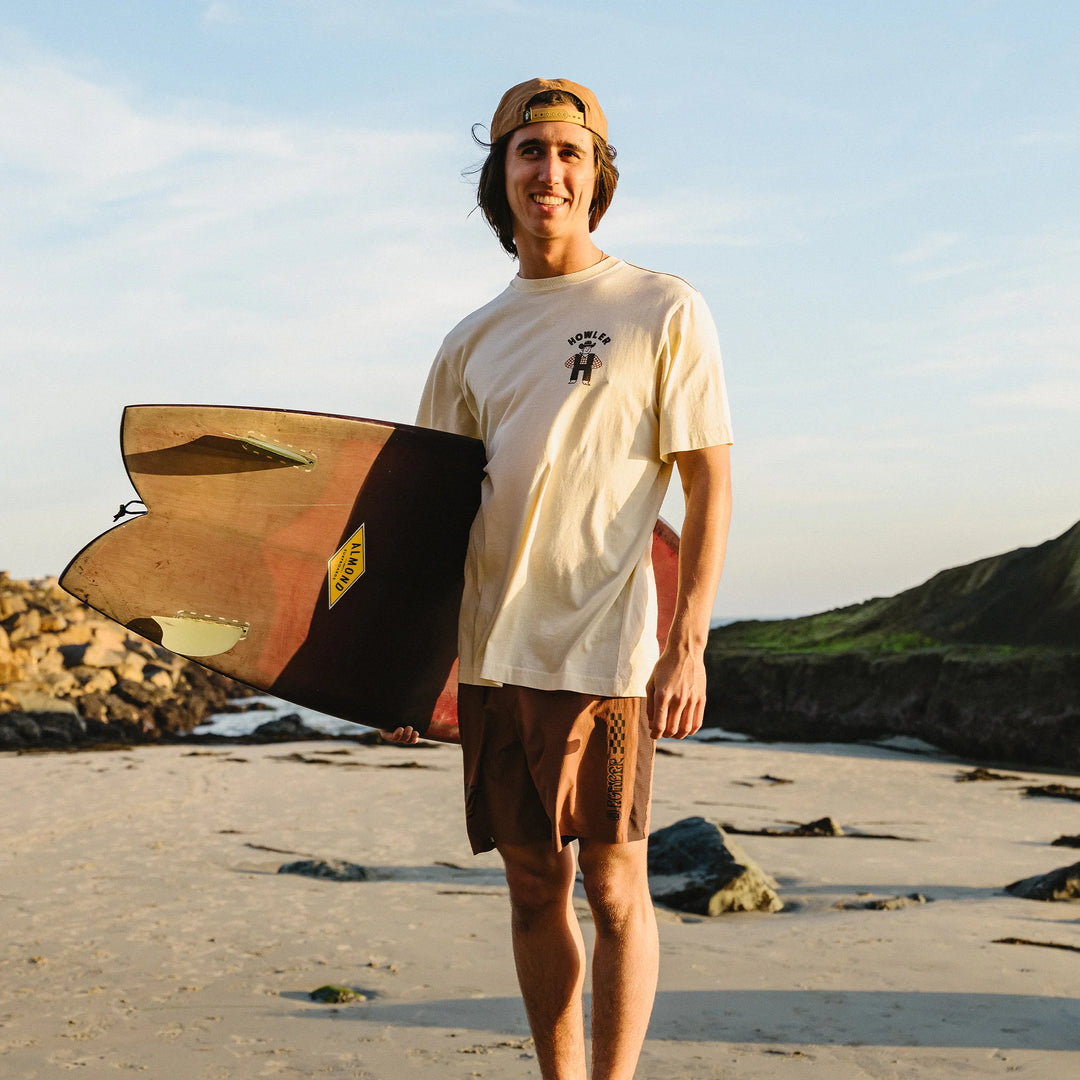 Person holding a surfboard on a beach with a scenic background