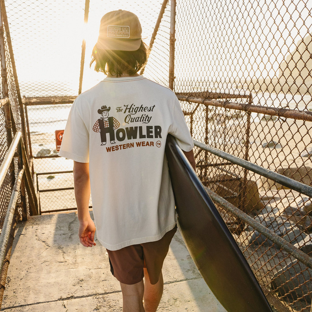 Person wearing a 'Howler Western Wear' t-shirt walking on a bridge.