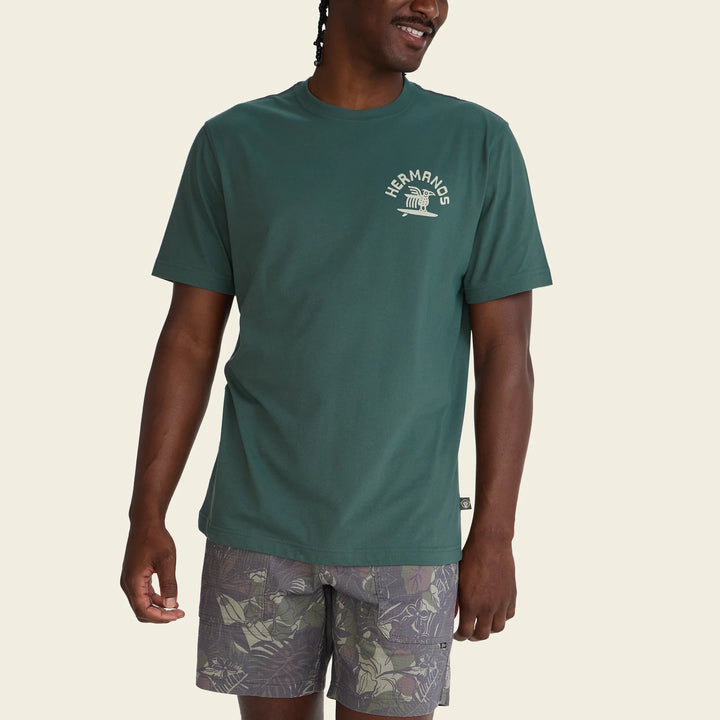 Man wearing a green t-shirt with a logo on a beige background
