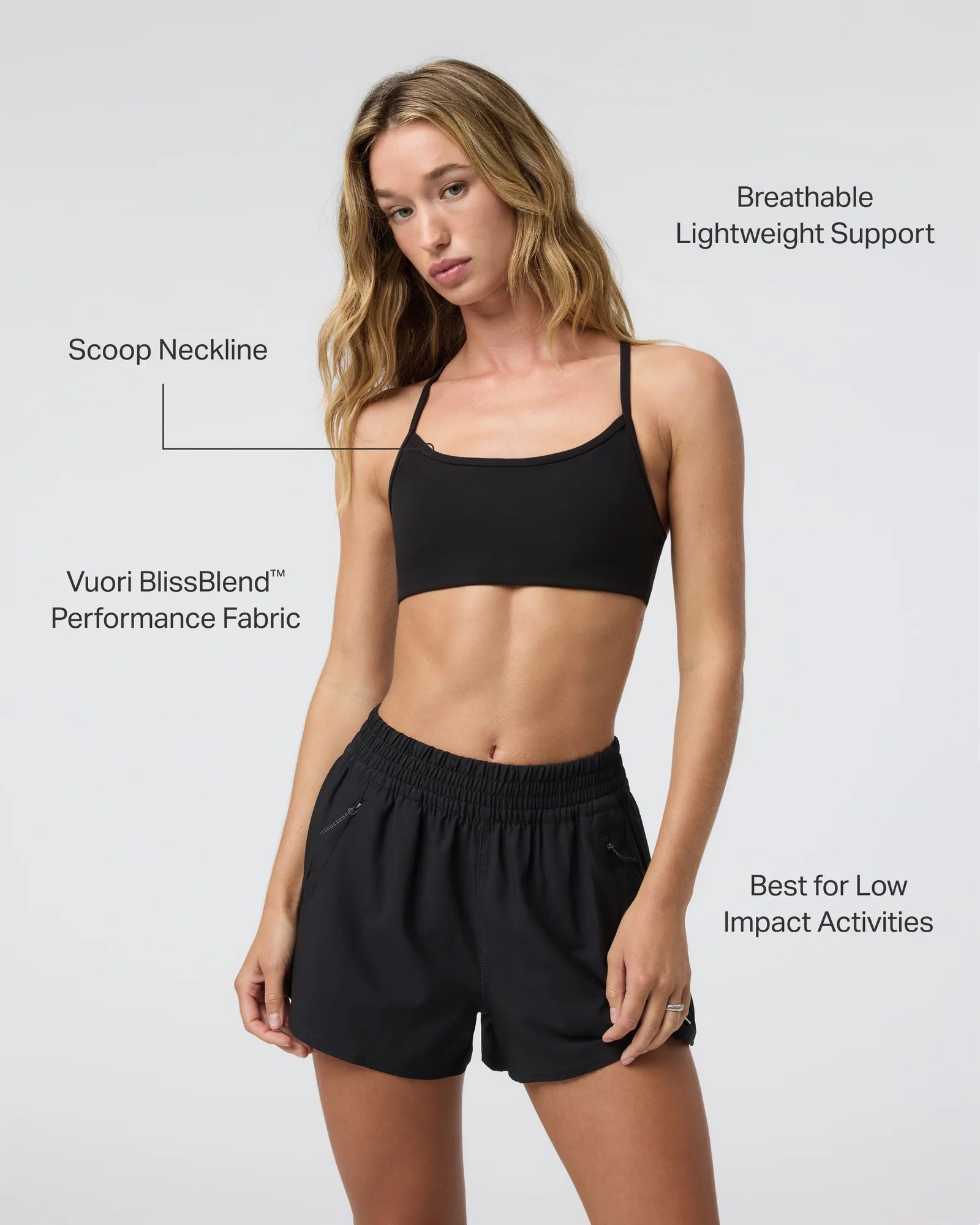 Woman wearing a black sports bra and shorts with text highlighting features on a white background