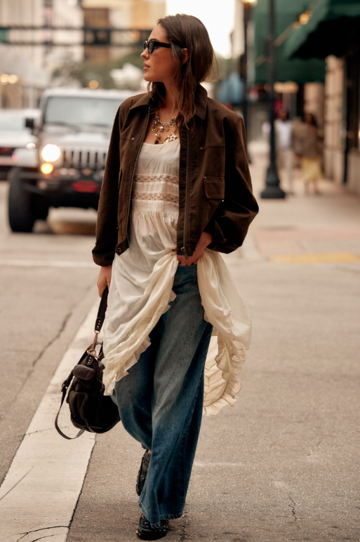 Blair Vegan Suede Sierra Jacket in Chocolate Torte on model wearing an ivory dress and jeans walking down a street. 