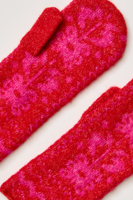 A pair of fuzzy knit fingerless gloves in a vibrant red and hot pink floral pattern, shown on a plain white background.