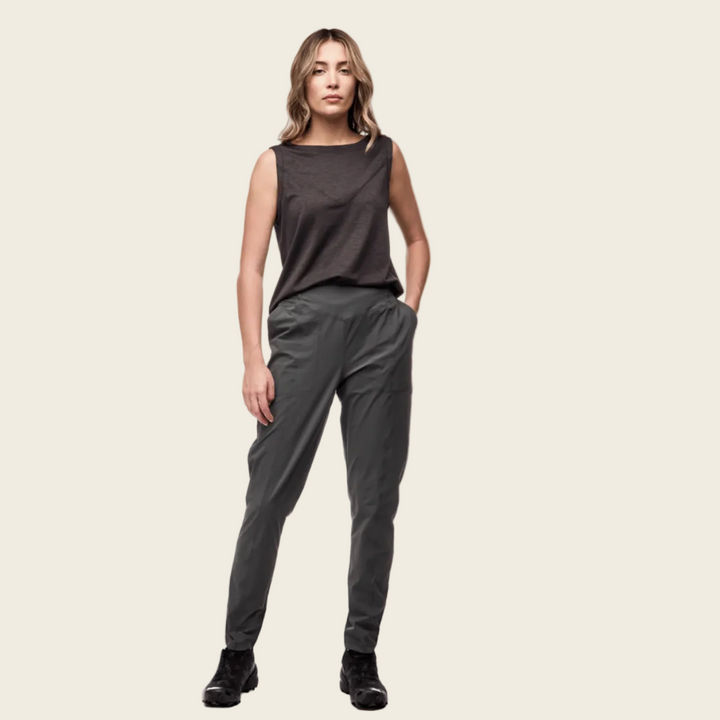 Woman wearing a dark sleeveless top and gray pants on a white background