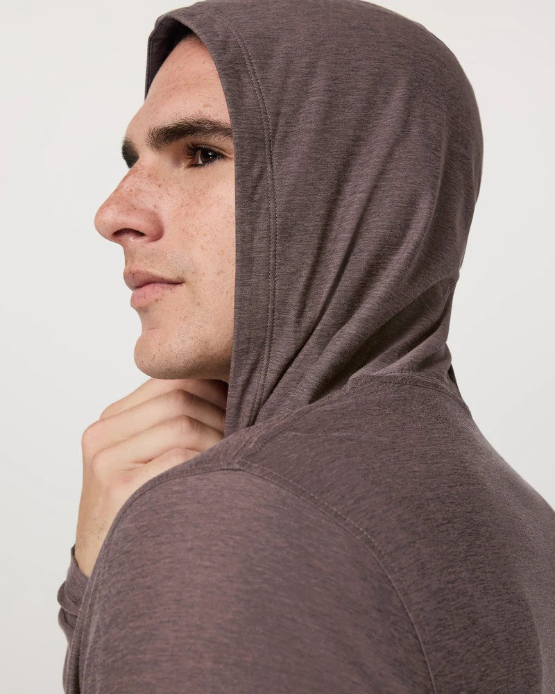 Man wearing a brown hooded garment against a plain background