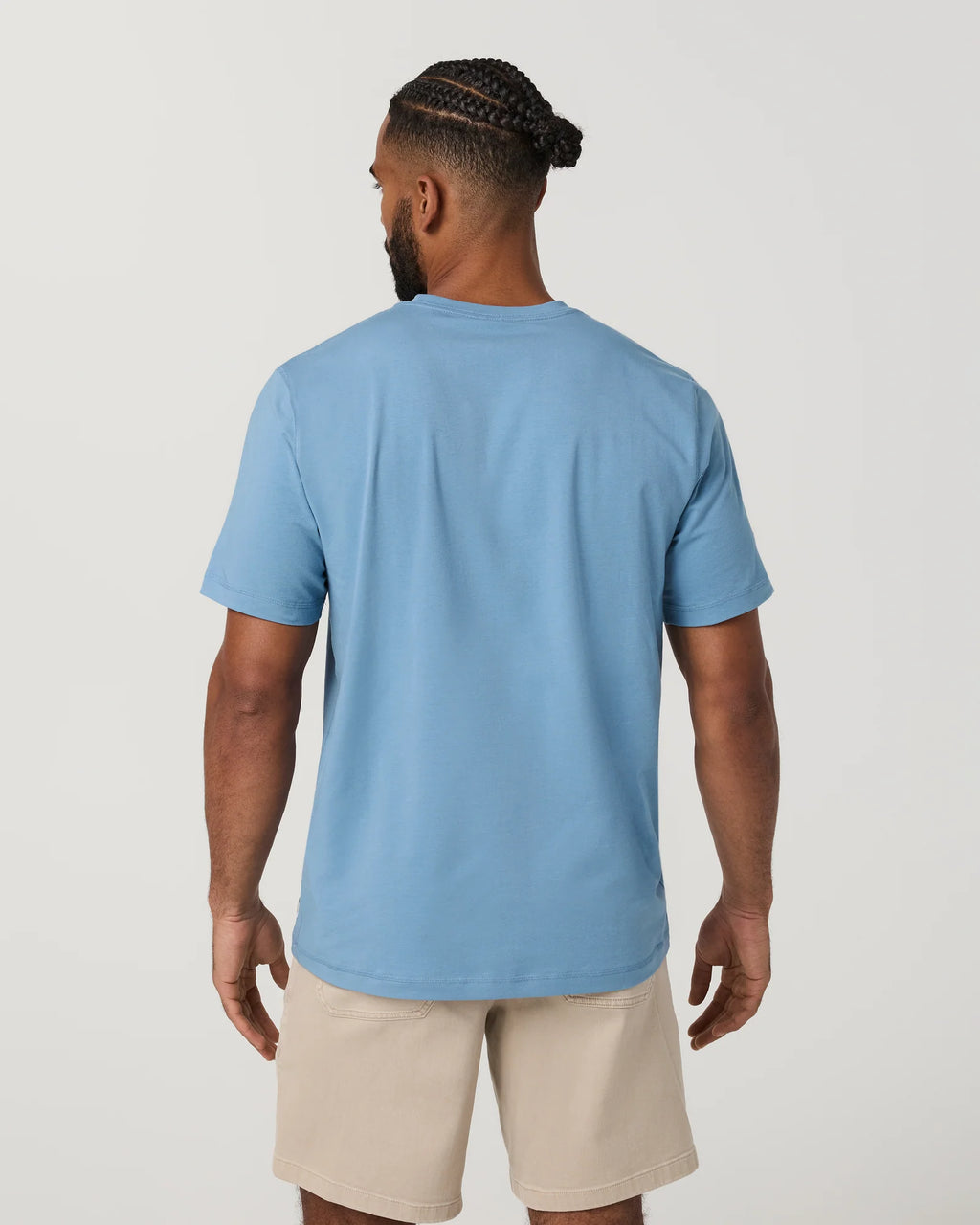 Man wearing a blue t-shirt and beige shorts on a plain background