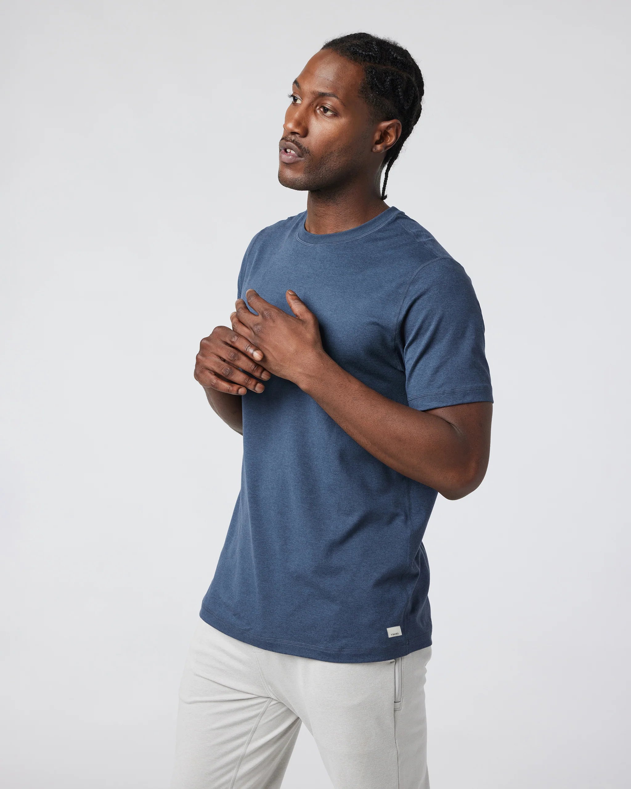 Man wearing a blue t-shirt and white pants against a plain background