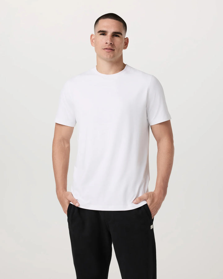 Man wearing a white t-shirt and black pants against a plain background
