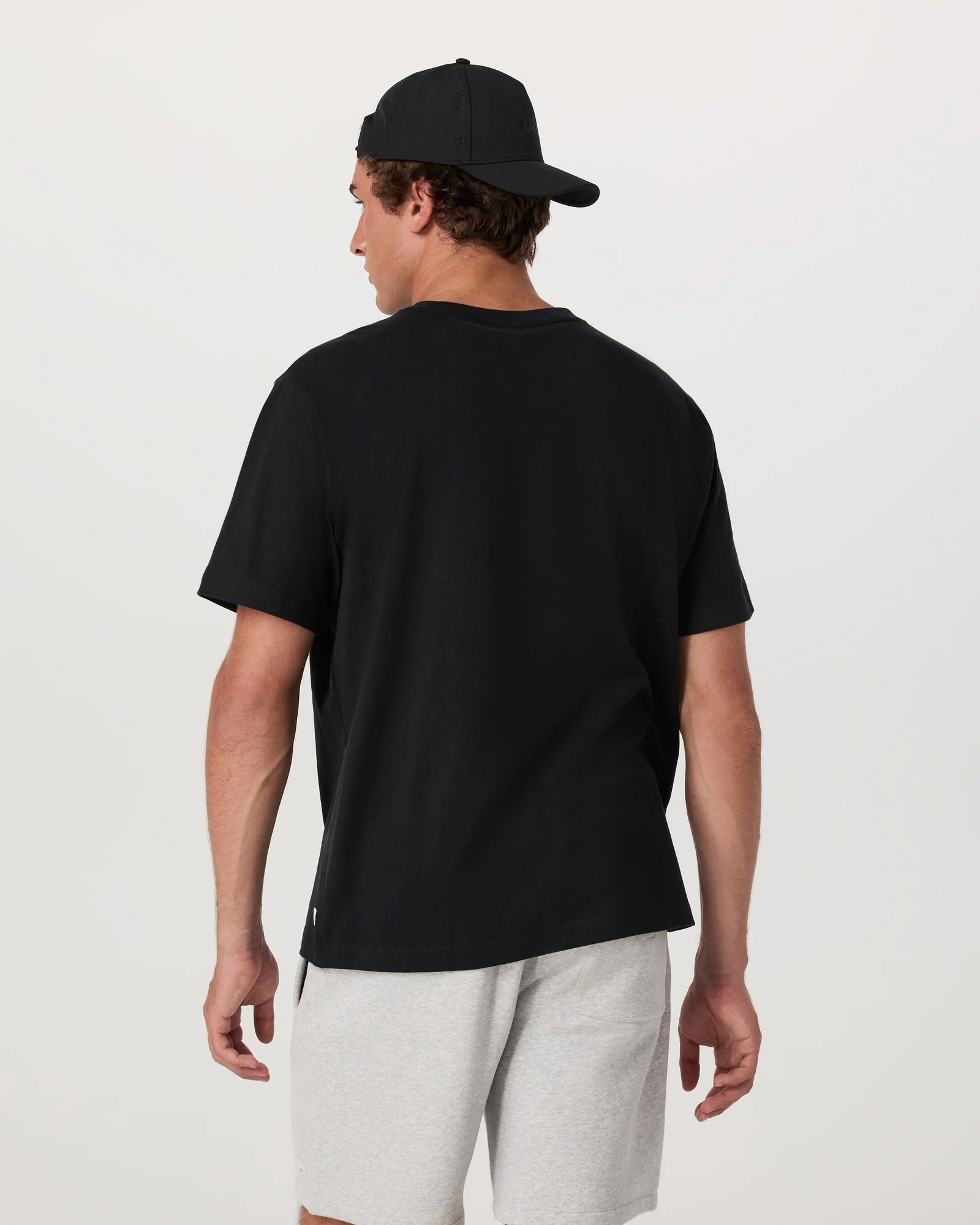 Person wearing a black t-shirt and cap on a plain background