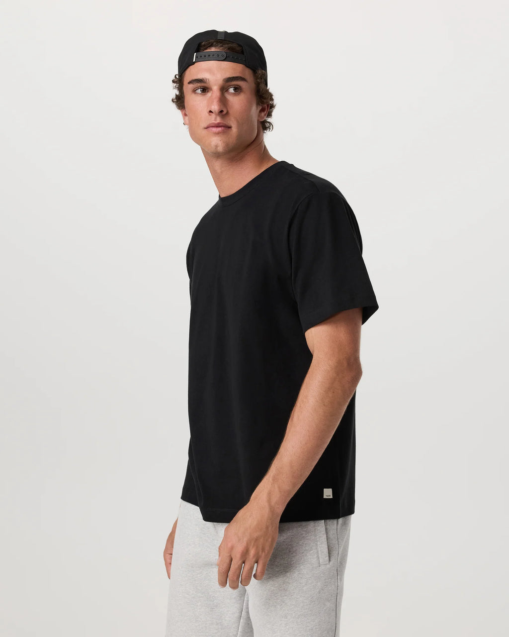 Man wearing a black t-shirt and gray pants on a white background