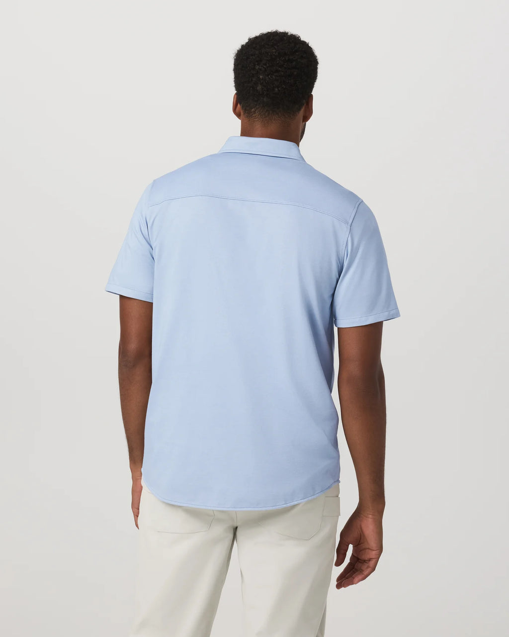 Man wearing a light blue polo shirt on a plain background