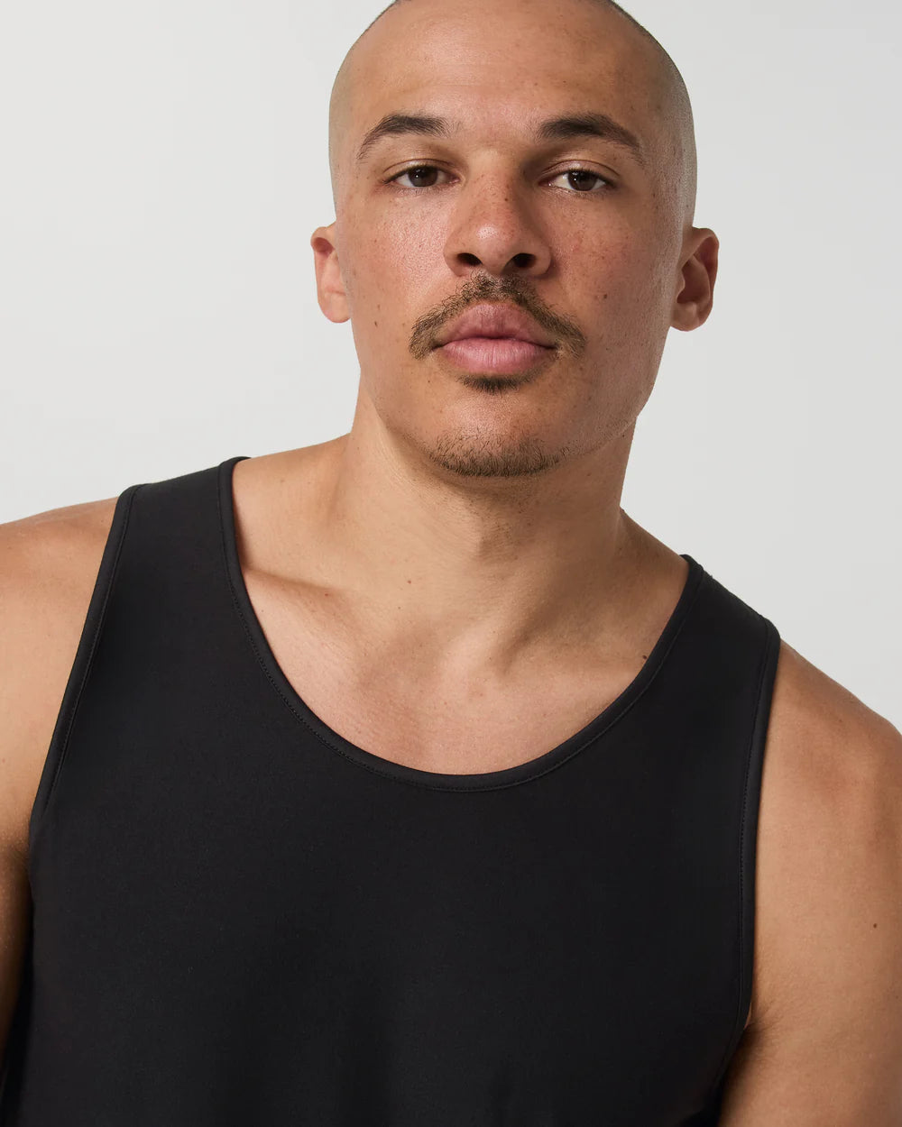 Man wearing a black tank top against a plain background