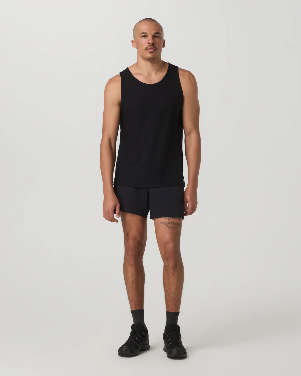 Man wearing a black tank top and shorts on a white background