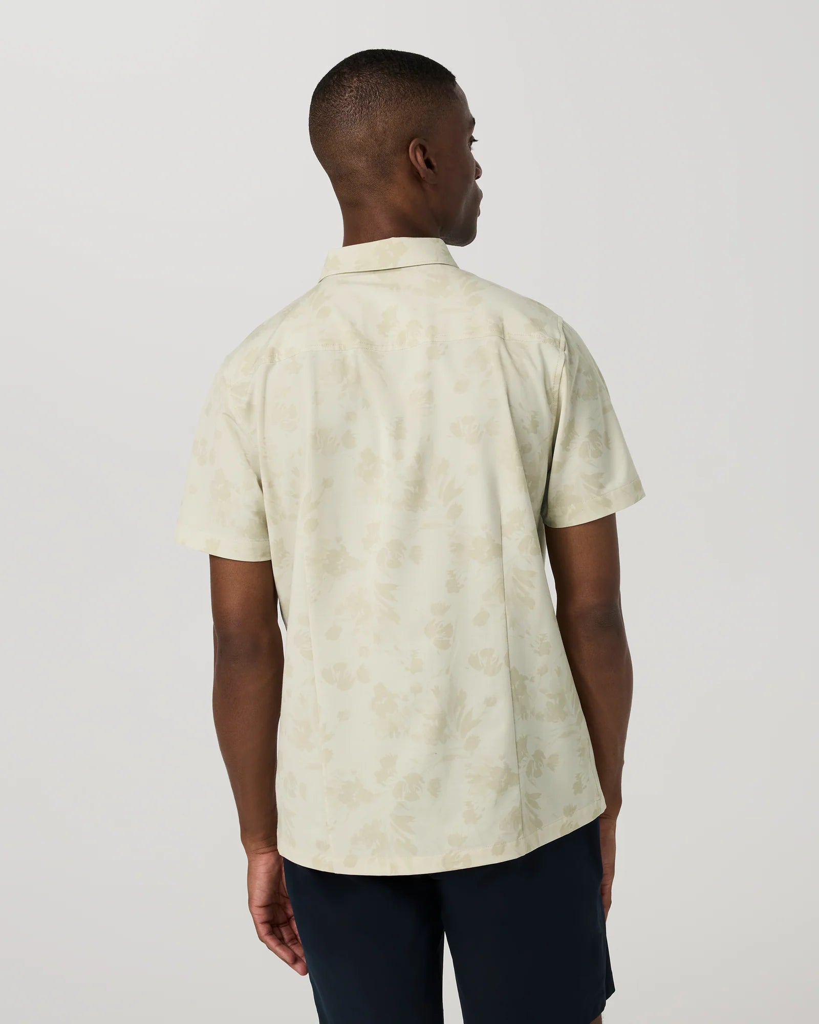 Man wearing a light-colored patterned shirt against a plain background