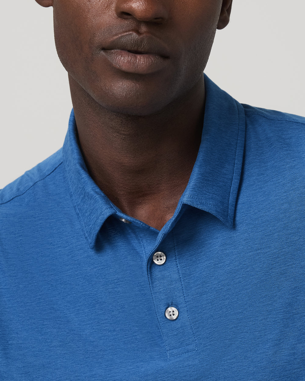 Man wearing a blue polo shirt against a neutral background