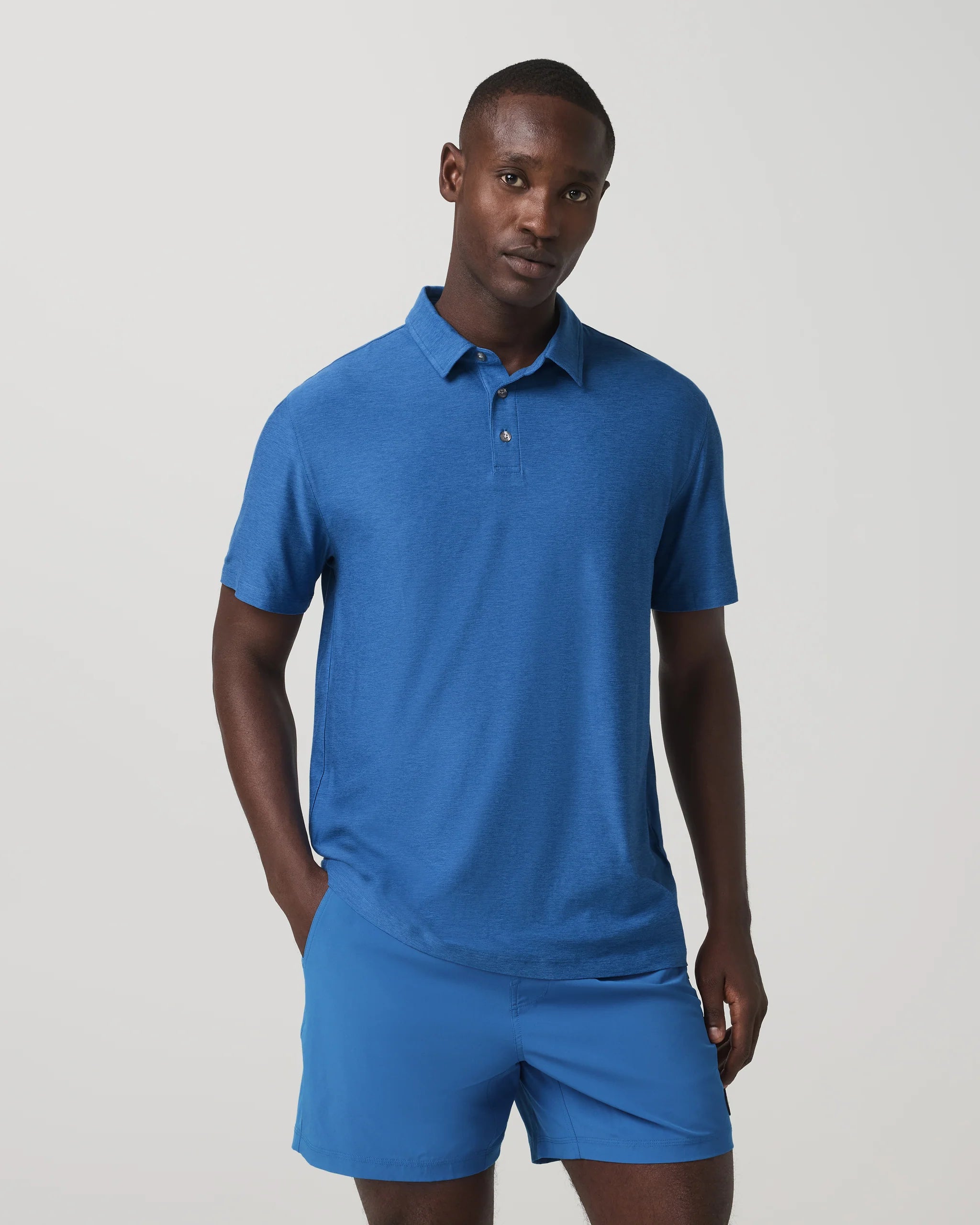 Man wearing a blue polo shirt and shorts on a light gray background