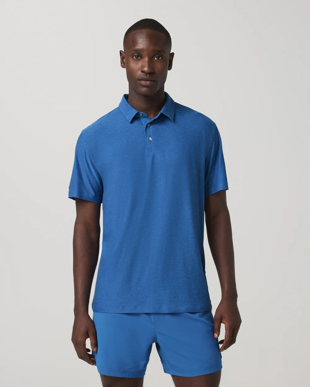 Man wearing a blue polo shirt and shorts on a light gray background