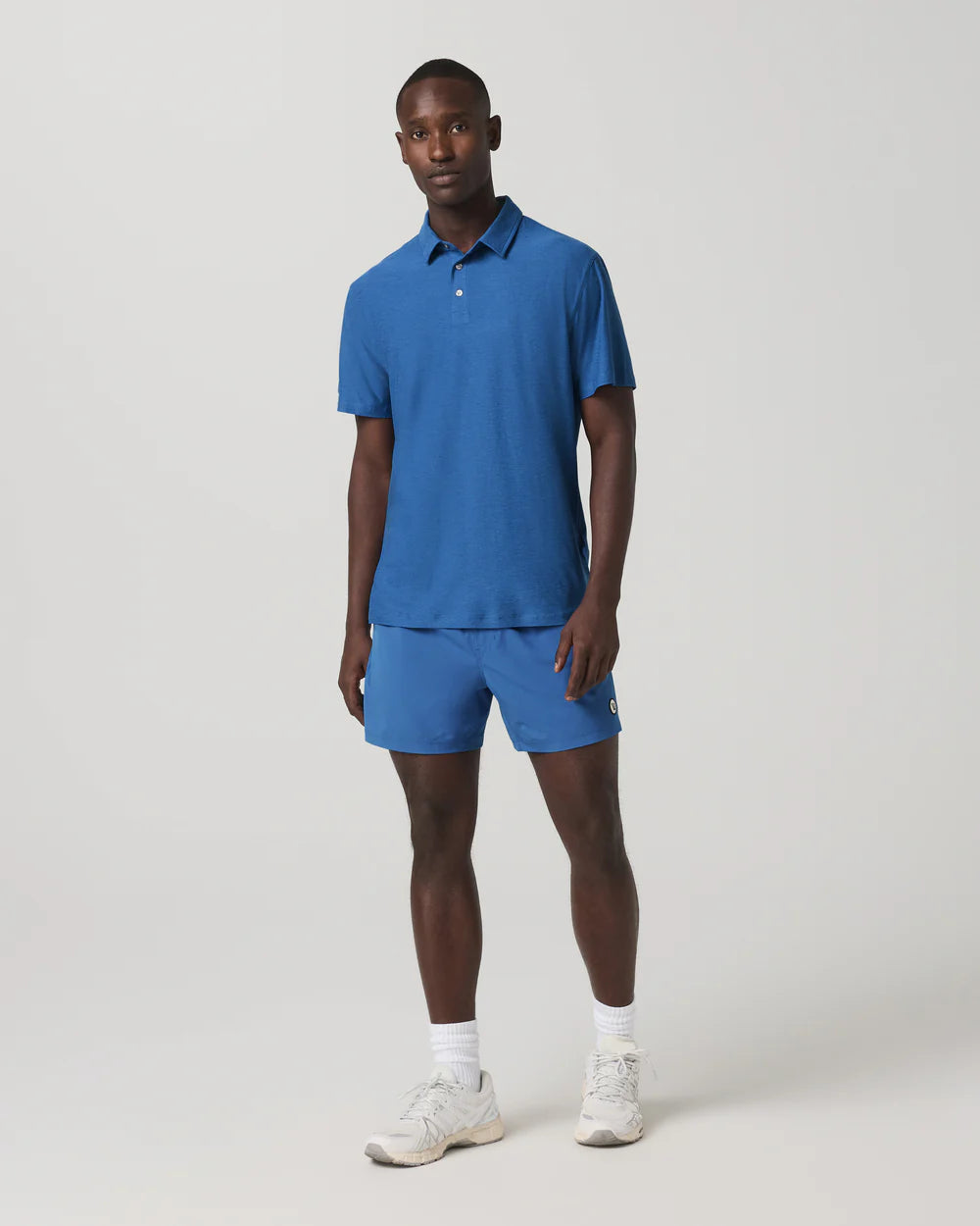 Man wearing a blue polo shirt and shorts set on a white background