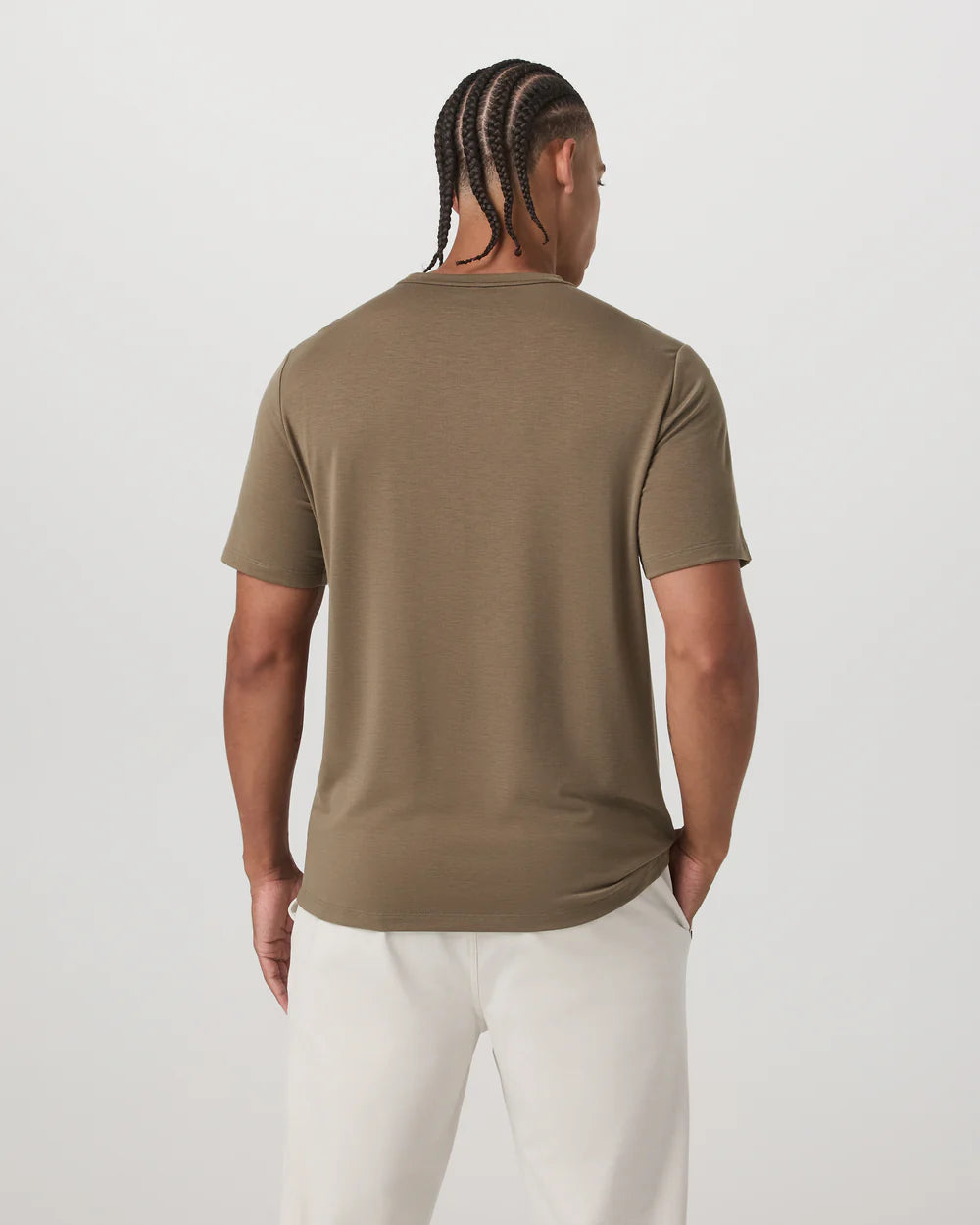 Person wearing a brown t-shirt and white pants on a light gray background