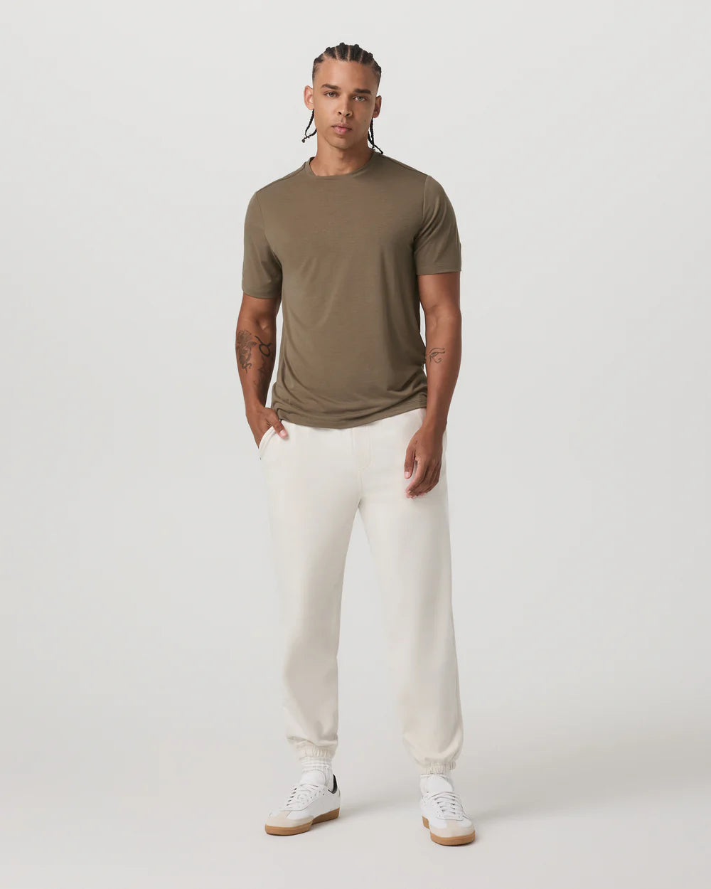 Man wearing a green t-shirt and white pants on a white background