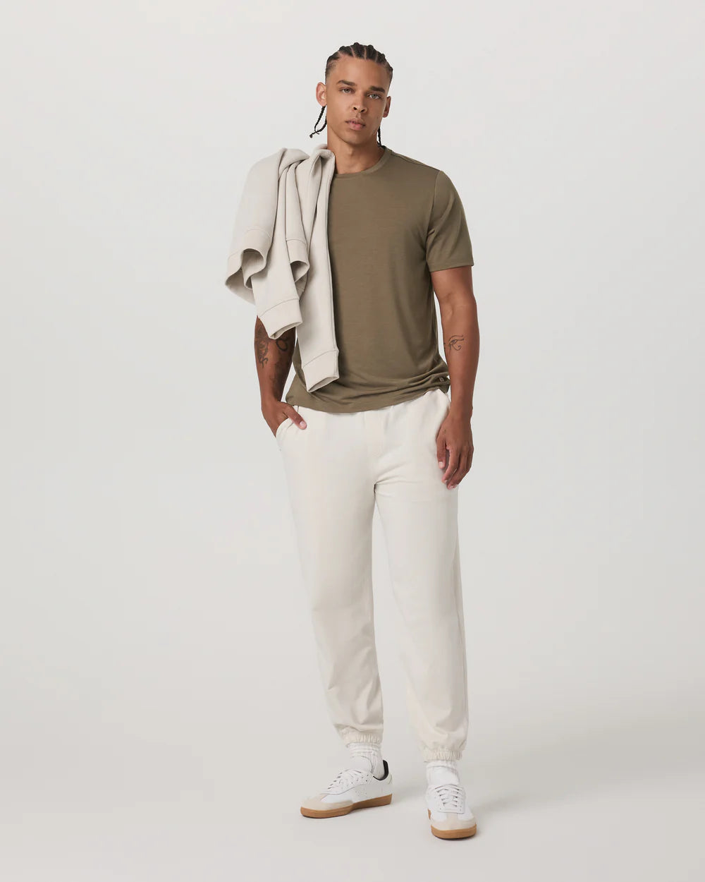 Man wearing a green t-shirt, white pants, and white sneakers on a plain background