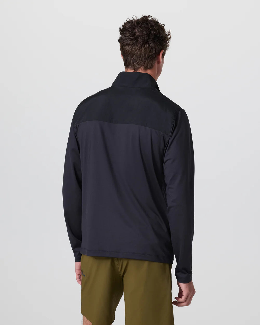 Person wearing a black jacket and green shorts on a light gray background