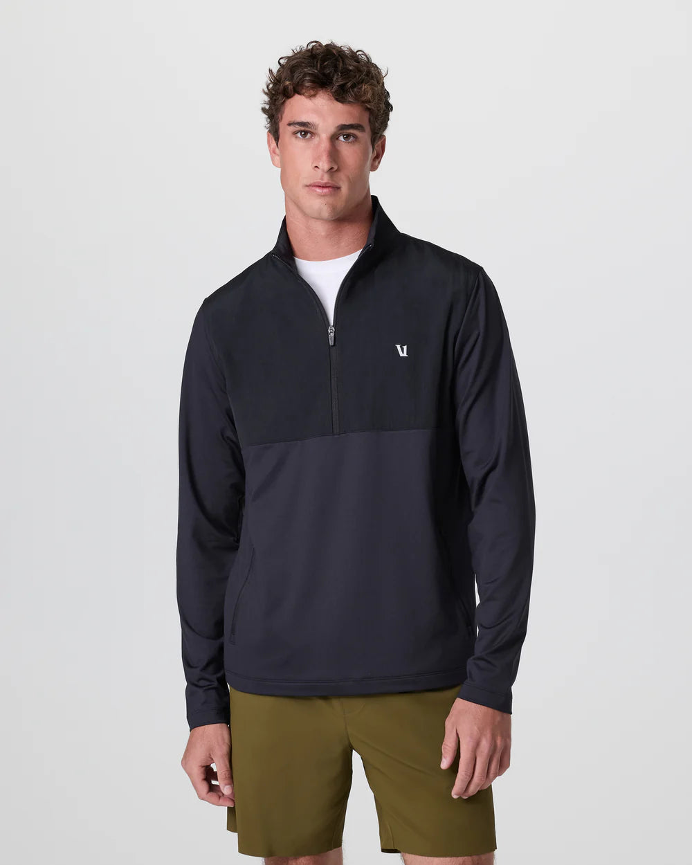 Man wearing a dark blue pullover with a logo on a light gray background
