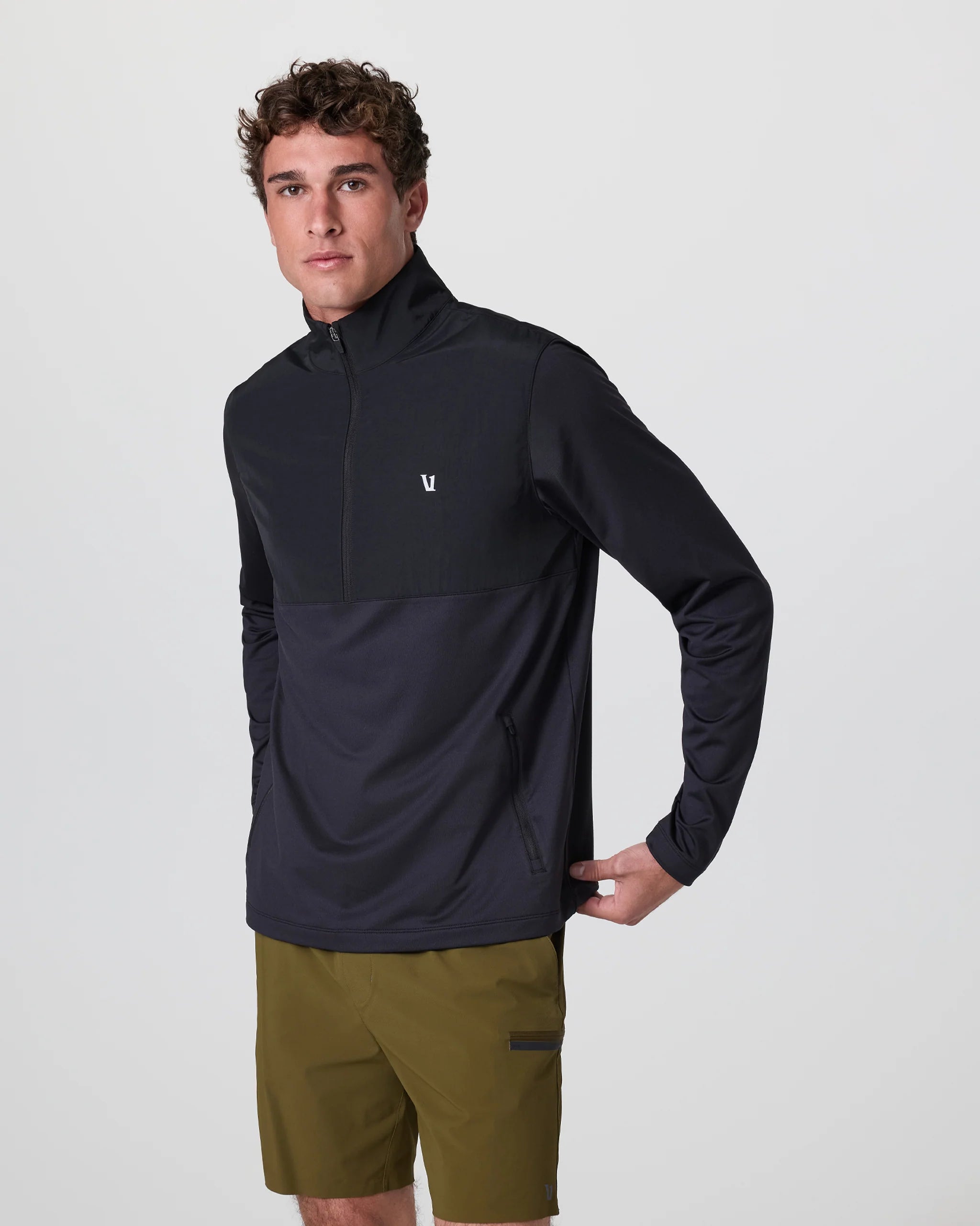 Man wearing a black pullover and green shorts on a light gray background