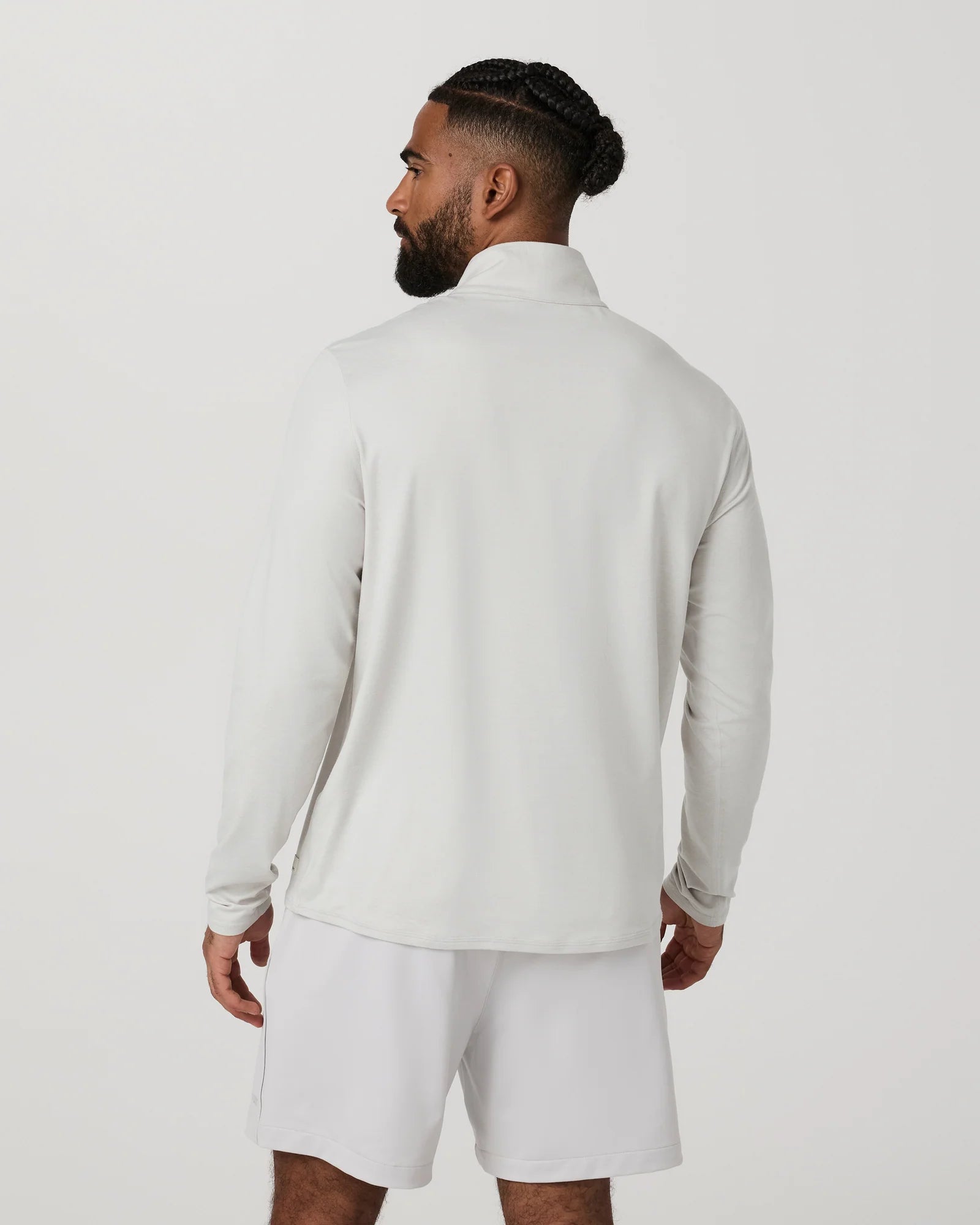 A man wearing a light gray long-sleeve athletic pullover and matching shorts, shown from the back against a plain light gray studio background.