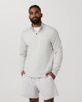 A man wearing a light gray quarter-zip long-sleeve shirt and matching light gray shorts, standing against a plain light gray studio background.