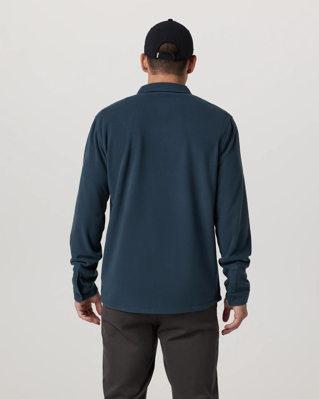 Person wearing a dark blue long-sleeve shirt and black cap on a light gray background