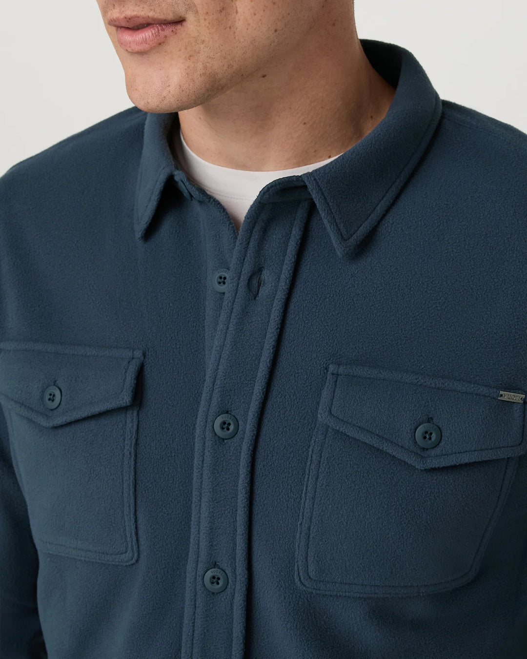 Navy blue shirt with collar and front pockets on a neutral background
