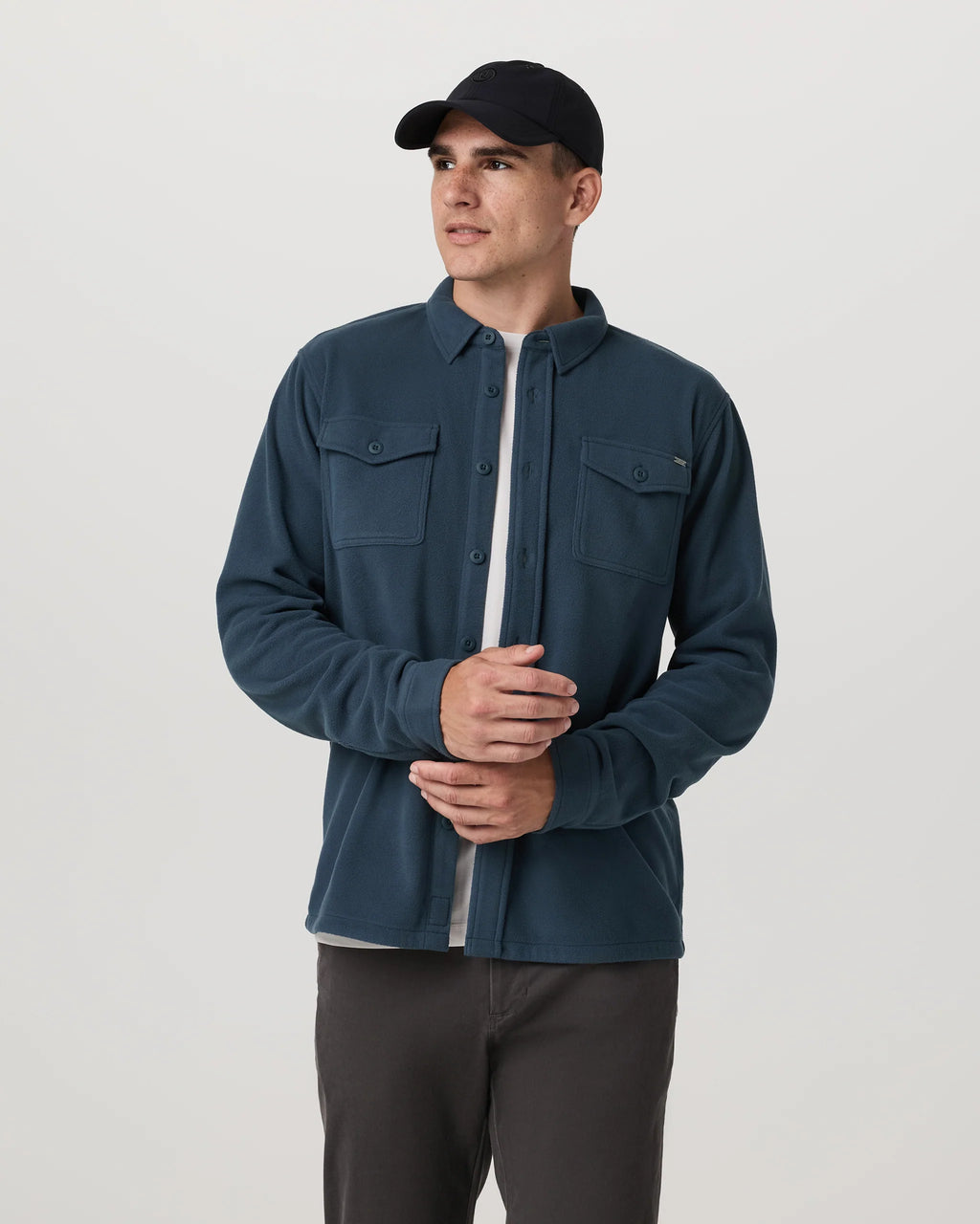 Man wearing a blue shirt and black cap on a white background