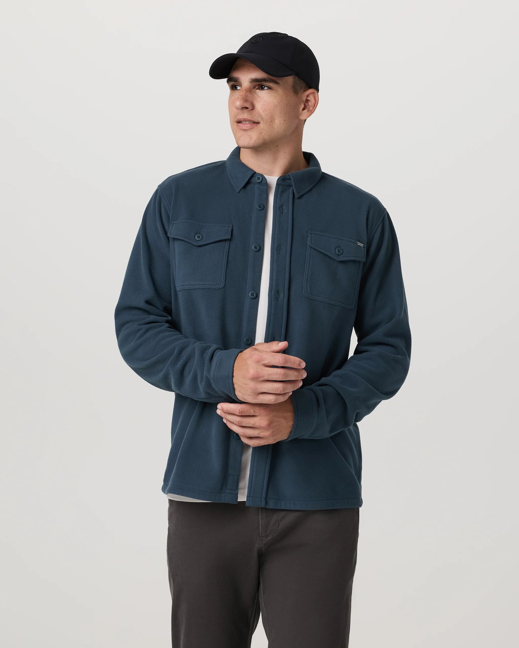 Man wearing a blue shirt and black cap on a white background