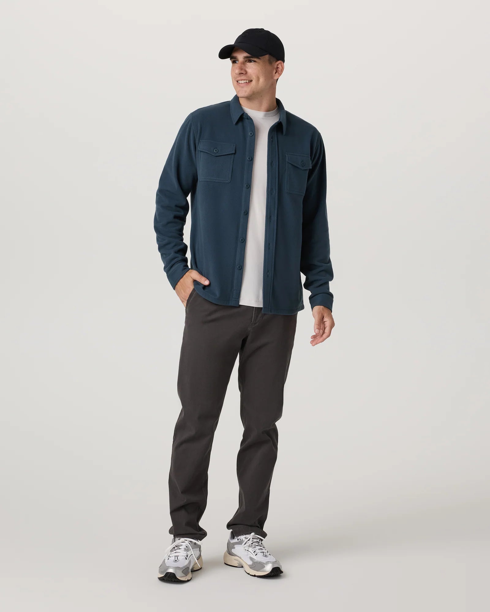 Man wearing a blue shirt, gray pants, and a black cap on a white background