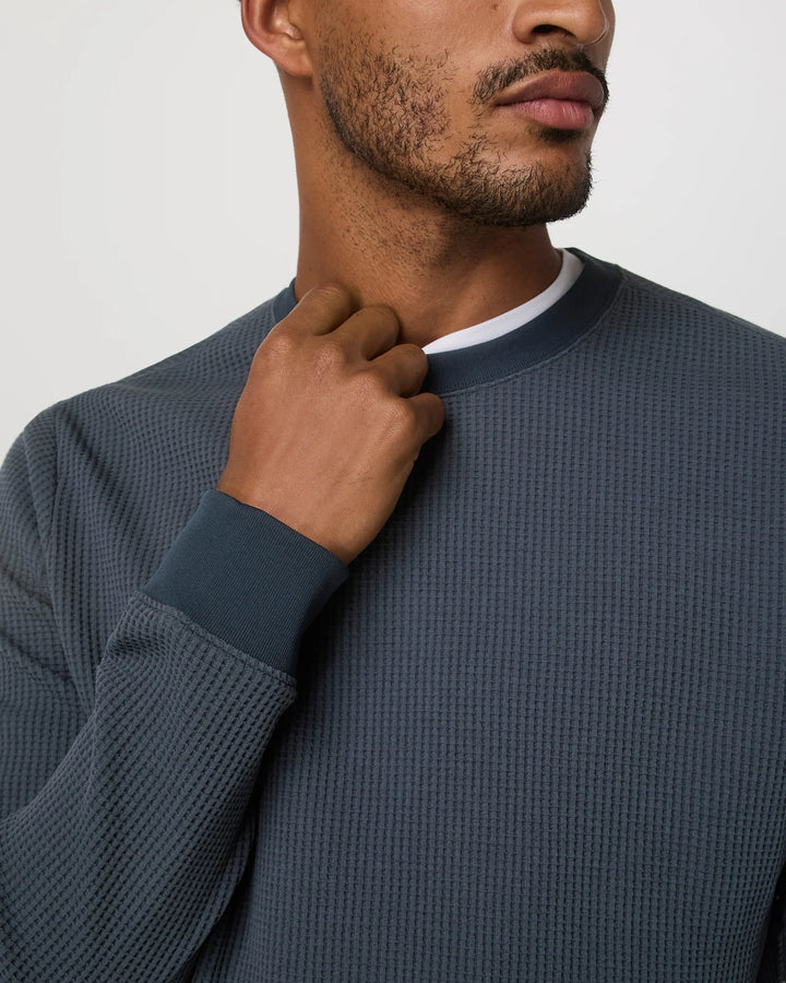 Man wearing a textured navy sweater against a plain background