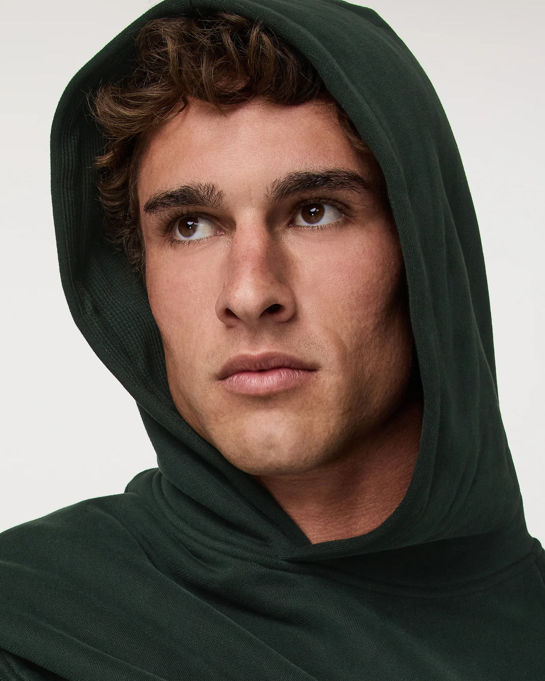 Man wearing a green hooded garment against a white background